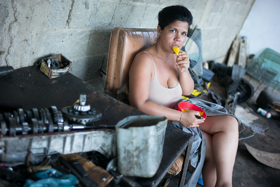 Woman eats a "noise reliever" (mango) at a mechanic workshop at Carúpano, Venezuela. Photo by Andrés Kerese.