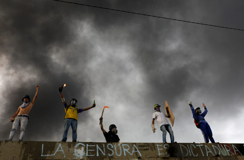 Demonstrators gesture to riot security forces while rallying against President Nicolas Maduro over a graffiti that reads "censorship is dictatorship" in Caracas , Venezuela, May 27, 2017. REUTERS/Carlos Garcia Rawlins -